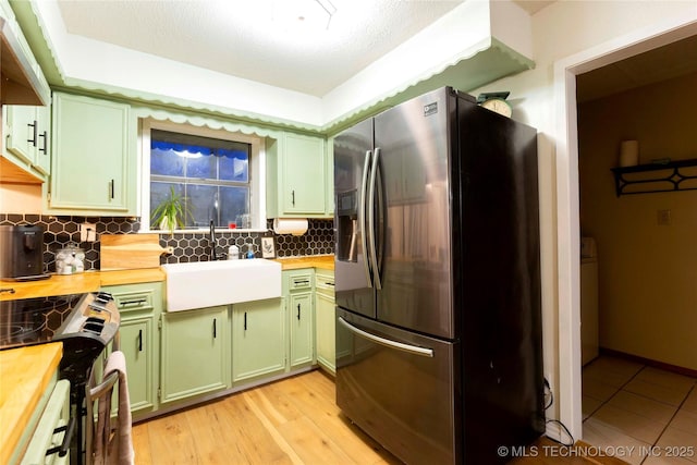 kitchen featuring butcher block counters, sink, tasteful backsplash, appliances with stainless steel finishes, and green cabinets