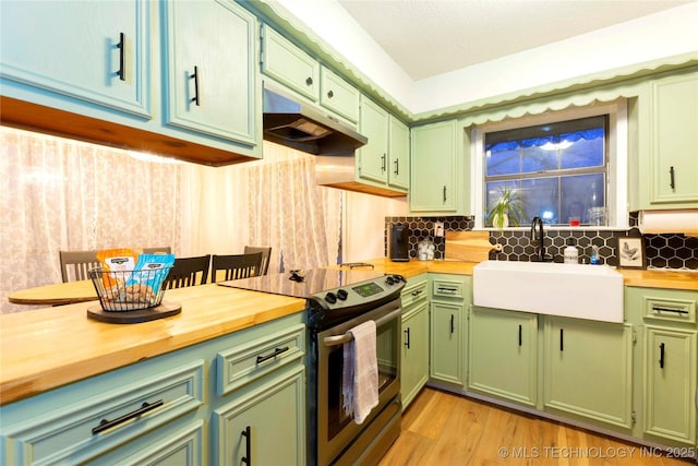 kitchen featuring wood counters, sink, green cabinetry, and stainless steel electric range oven