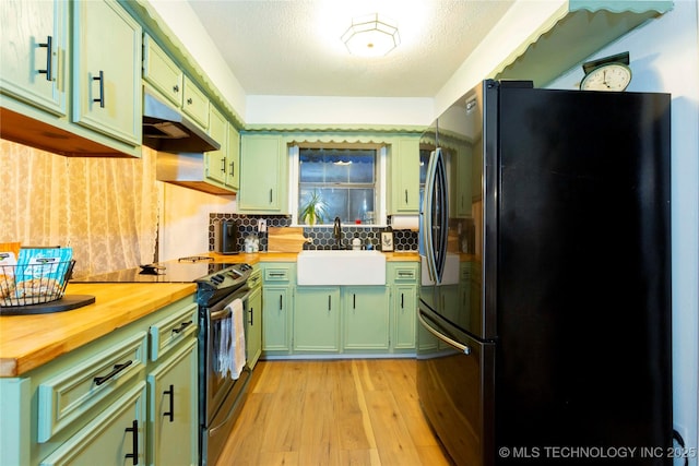 kitchen featuring black refrigerator, stainless steel range with electric stovetop, butcher block countertops, and green cabinetry