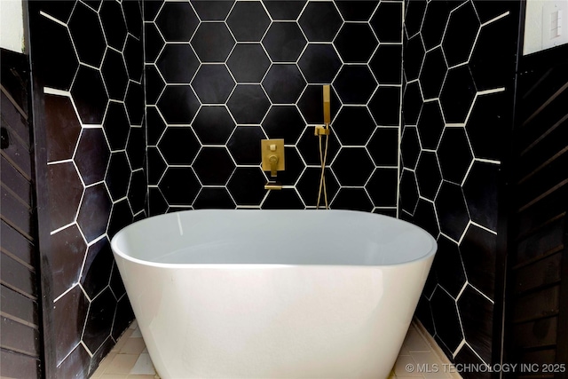 bathroom featuring tile patterned flooring, a bathtub, and tile walls