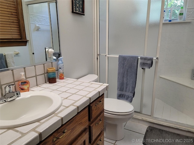 bathroom with a shower with shower door, decorative backsplash, vanity, toilet, and tile patterned floors