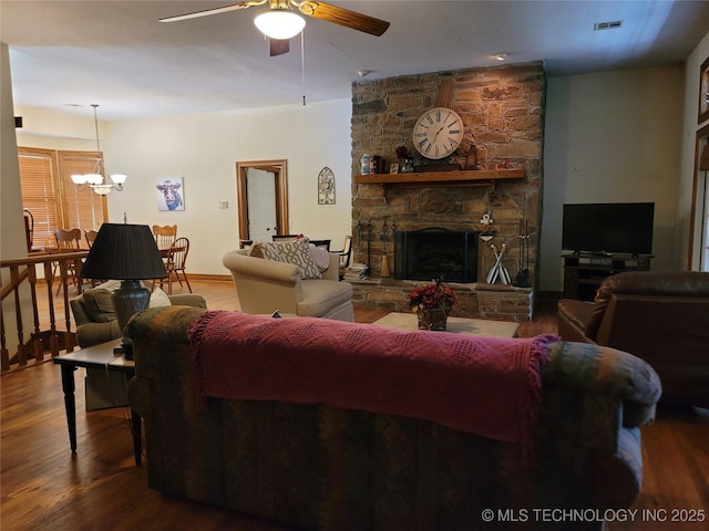 living room with ceiling fan with notable chandelier, a fireplace, and hardwood / wood-style floors