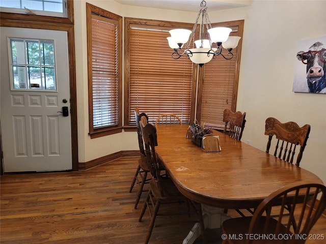 dining area with dark wood-type flooring and a chandelier