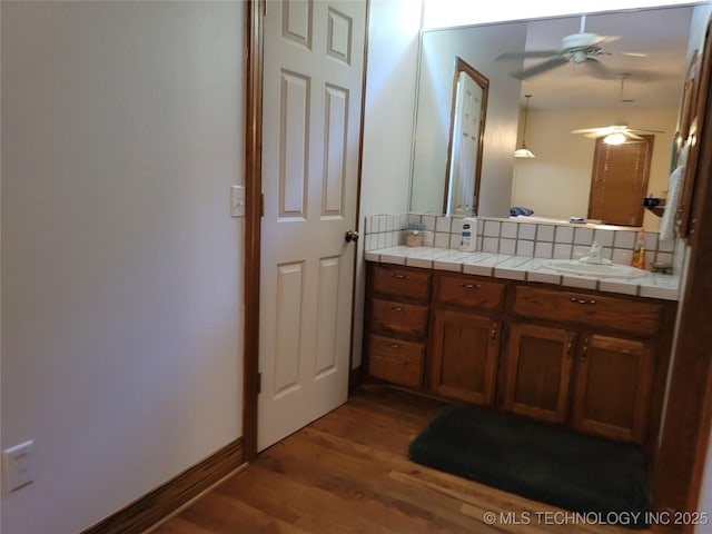 bathroom with tasteful backsplash, wood-type flooring, vanity, and ceiling fan