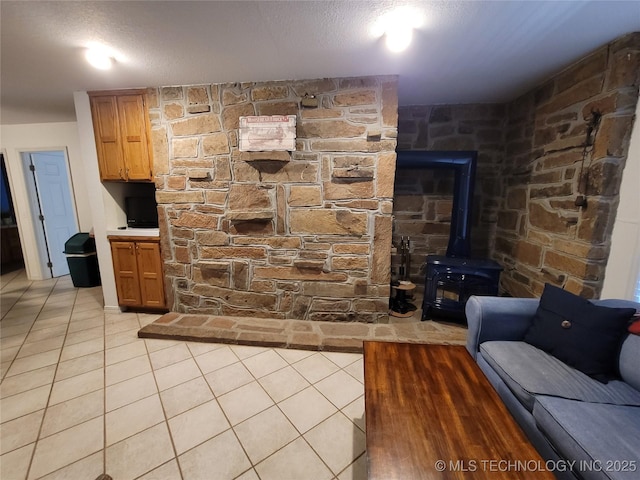 living room featuring a wood stove, light tile patterned floors, and a textured ceiling