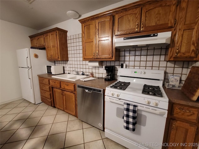 kitchen featuring sink, white appliances, light tile patterned floors, and decorative backsplash