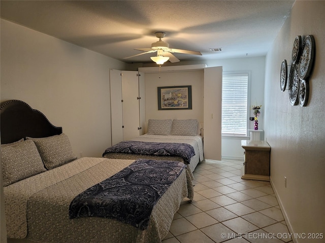 tiled bedroom featuring ceiling fan and a textured ceiling