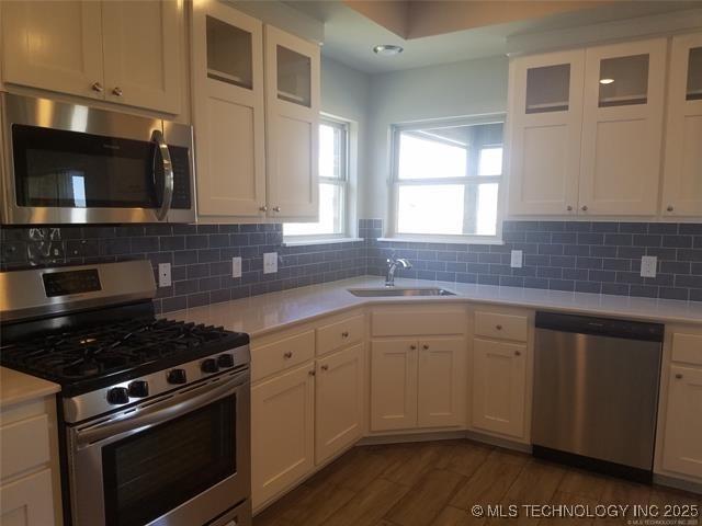 kitchen featuring sink, dark wood-type flooring, appliances with stainless steel finishes, tasteful backsplash, and white cabinets