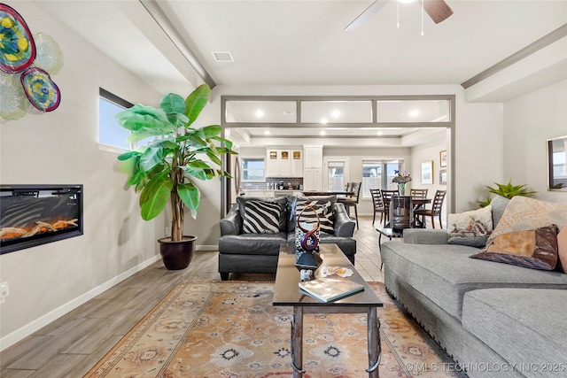 living room with beam ceiling, wood-type flooring, and ceiling fan