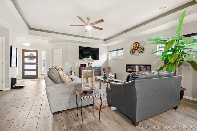 living room with ceiling fan and a tray ceiling