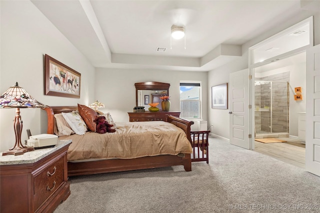 bedroom featuring connected bathroom, light carpet, ceiling fan, and a tray ceiling