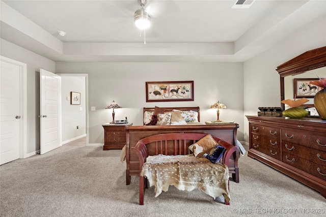 bedroom featuring ceiling fan, light colored carpet, and a tray ceiling