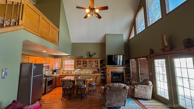 living room with a towering ceiling, ceiling fan, and light hardwood / wood-style flooring