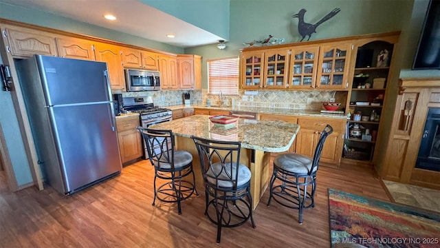 kitchen with light hardwood / wood-style flooring, a kitchen breakfast bar, a center island, and appliances with stainless steel finishes