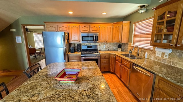 kitchen with sink, stone counters, stainless steel appliances, a kitchen breakfast bar, and light hardwood / wood-style floors