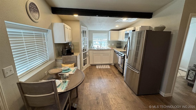 kitchen with white cabinetry, backsplash, beam ceiling, stainless steel appliances, and light hardwood / wood-style floors