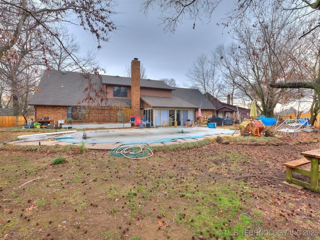 back of house with a fenced in pool, a patio area, fence, and a chimney