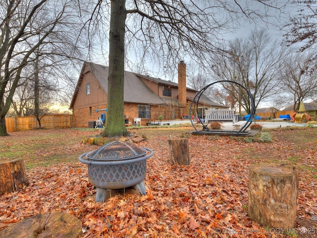 view of yard featuring central AC unit, an outdoor fire pit, and fence