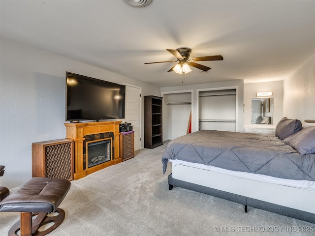 carpeted bedroom featuring a ceiling fan and a fireplace