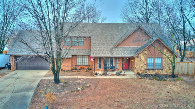 view of front of house with a shingled roof, stone siding, and fence