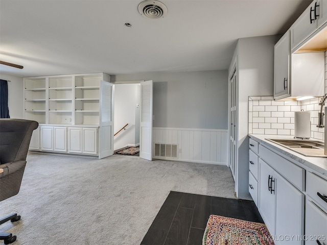 kitchen with sink, decorative backsplash, white cabinets, and dark colored carpet