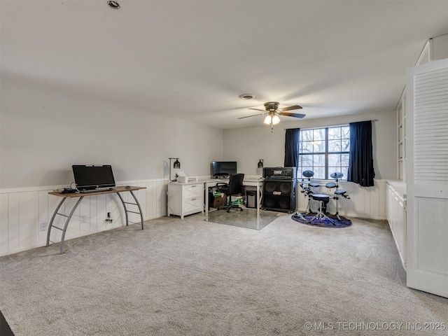 office area with a wainscoted wall, carpet, and a ceiling fan