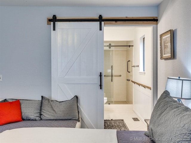 bedroom with a barn door and connected bathroom