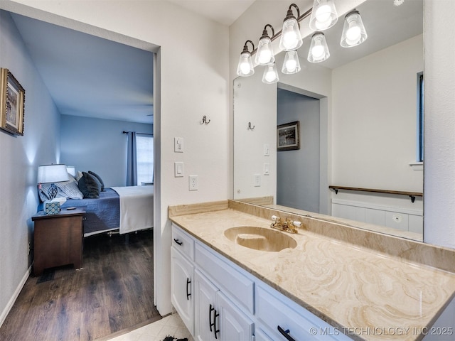 ensuite bathroom with wood finished floors, connected bathroom, vanity, and baseboards