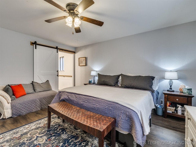 bedroom with dark wood-type flooring, ceiling fan, and a barn door