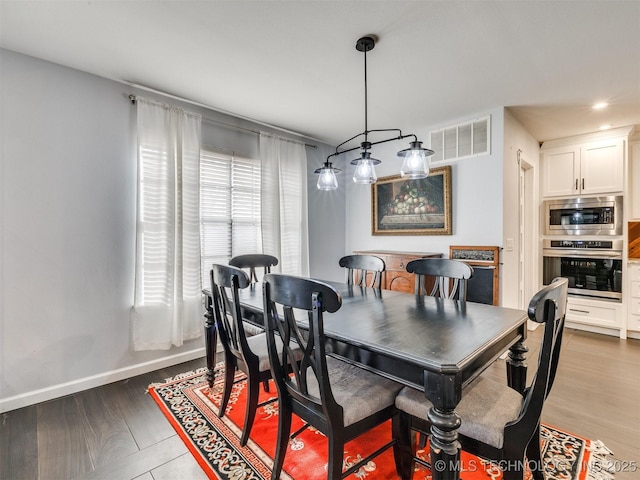 dining area featuring light wood finished floors, visible vents, and baseboards