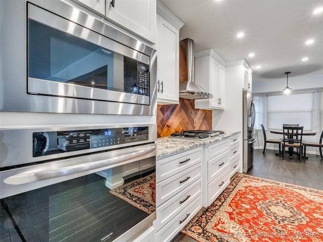 kitchen with stainless steel appliances, recessed lighting, backsplash, white cabinetry, and wall chimney exhaust hood