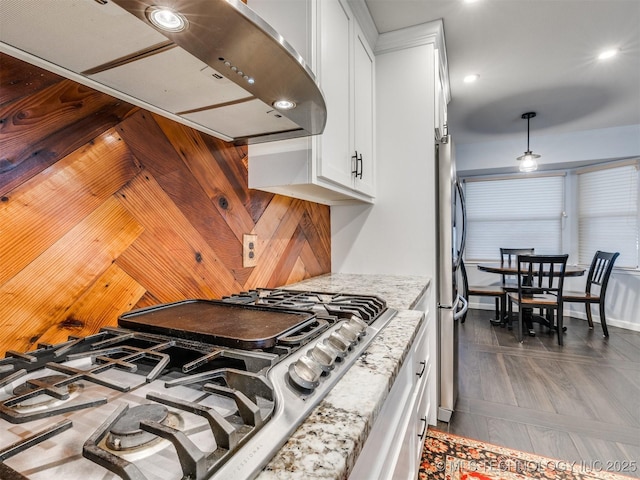 kitchen featuring cooktop, ventilation hood, stainless steel fridge, light stone countertops, and white cabinets