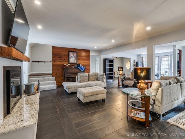 living room with a fireplace and wood walls