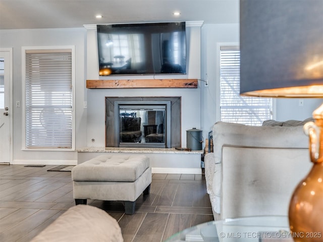 living area with recessed lighting, baseboards, and a glass covered fireplace