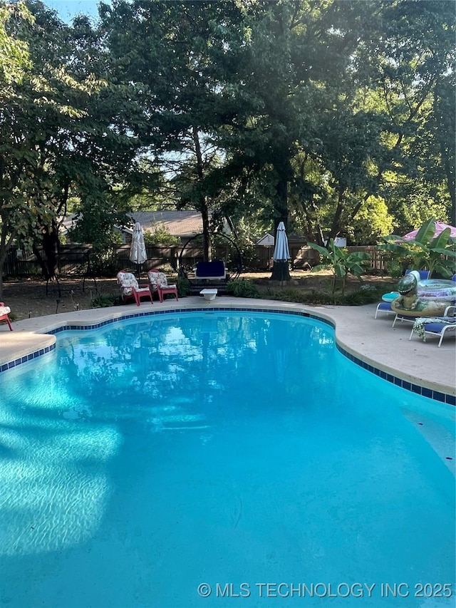 outdoor pool with a patio area and a diving board