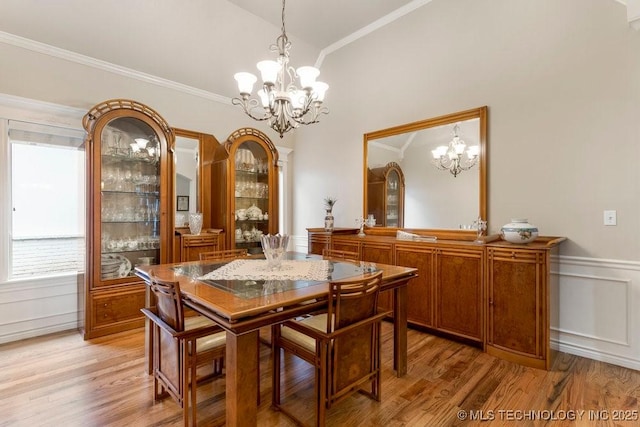 dining area featuring crown molding, lofted ceiling, light hardwood / wood-style floors, and a notable chandelier