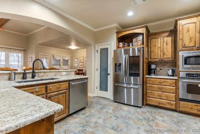 kitchen featuring sink, backsplash, stainless steel appliances, ornamental molding, and light stone countertops