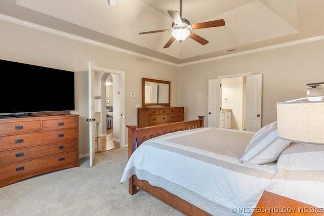 bedroom featuring a raised ceiling, ornamental molding, light carpet, and ensuite bathroom