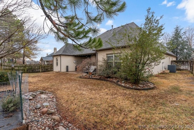 rear view of property with central AC unit and a lawn