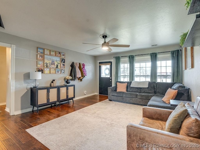 living room featuring dark wood-type flooring and ceiling fan