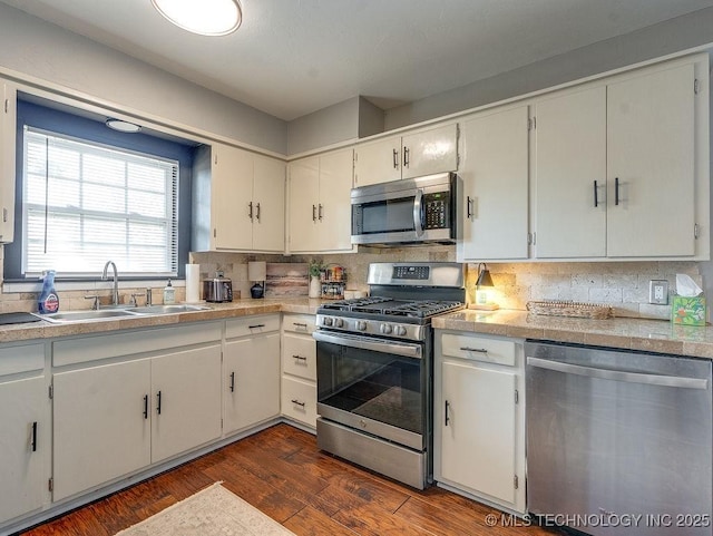 kitchen featuring sink, backsplash, stainless steel appliances, dark hardwood / wood-style floors, and white cabinets