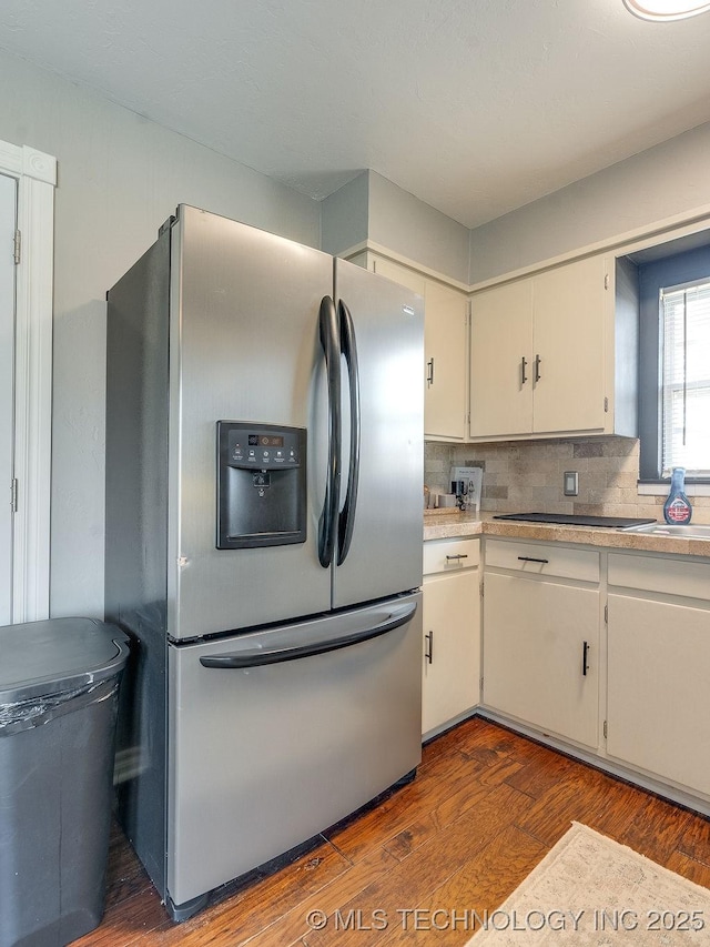 kitchen with hardwood / wood-style flooring, stainless steel refrigerator with ice dispenser, white cabinets, and decorative backsplash