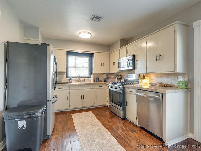 kitchen with tasteful backsplash, sink, dark wood-type flooring, and stainless steel appliances