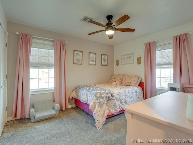 carpeted bedroom featuring multiple windows and ceiling fan