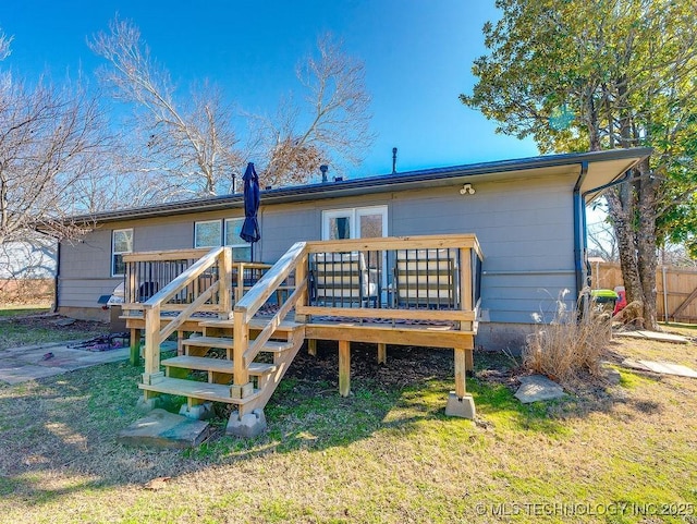 back of property featuring a wooden deck and a yard