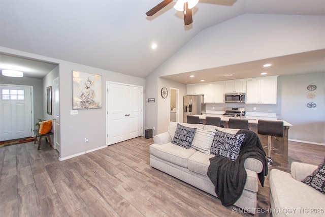 living room featuring light hardwood / wood-style flooring, high vaulted ceiling, and ceiling fan