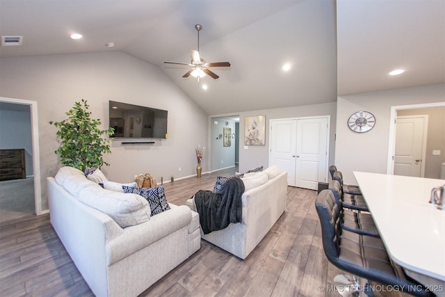 living room featuring hardwood / wood-style flooring, lofted ceiling, and ceiling fan