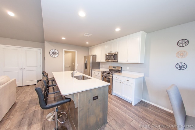 kitchen with white cabinetry, appliances with stainless steel finishes, a breakfast bar area, and a center island with sink