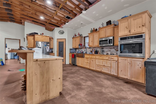 kitchen with appliances with stainless steel finishes, concrete flooring, light brown cabinetry, and decorative backsplash