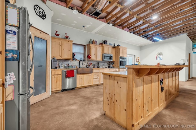 kitchen with light brown cabinetry, sink, a kitchen island, and appliances with stainless steel finishes